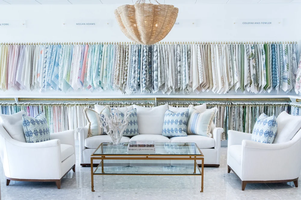 Hive Trade Showroom fabric wall with white and blue seating area in front, including blue and white pillows.