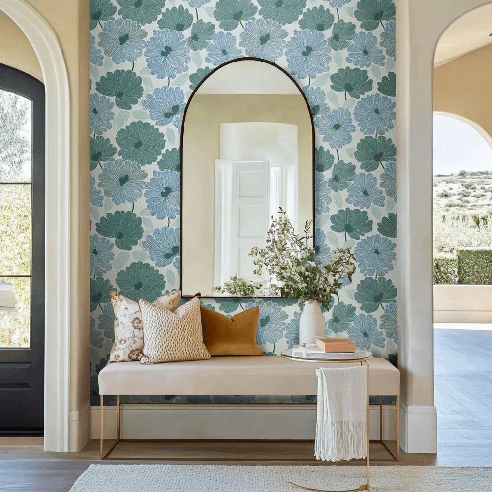 Blue Robyn floral wallpaper in a bright interior with a built-in bench, round mirror, and adjacent arched doorway.