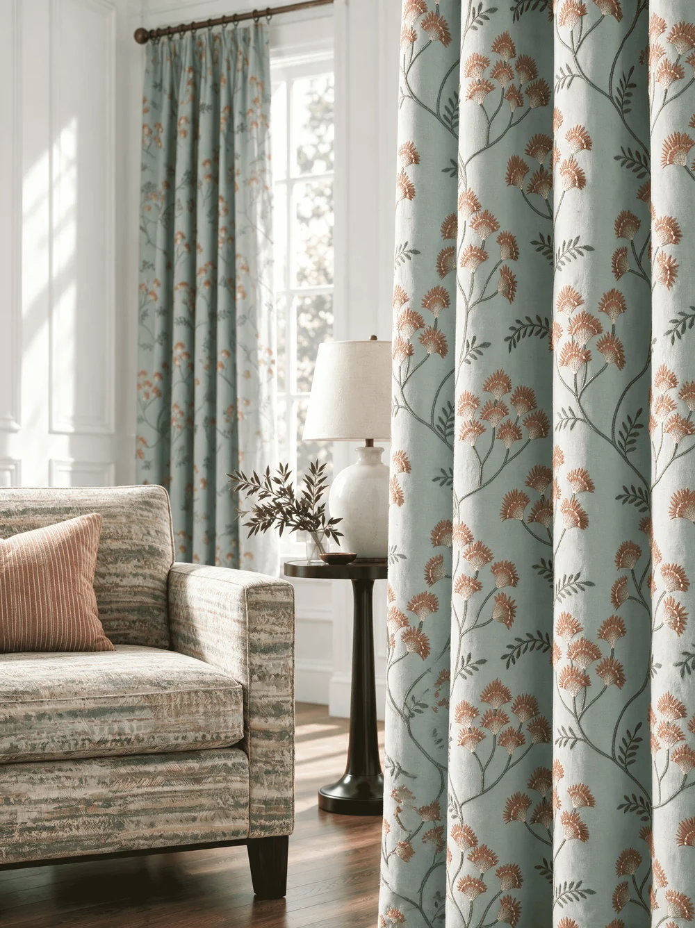 Pale blue floral full-length drapery panels beside a patterned armchair in a Stout Textiles Rainbow Library interior